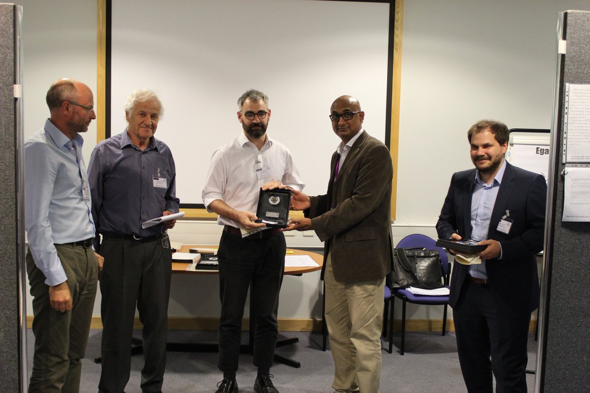 Group of male academics. An award is presented to one of them