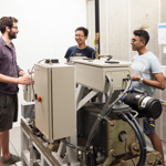 Group of DPhil students stood around big machine