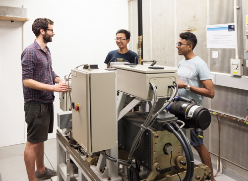 Group of DPhil students stood around big machine