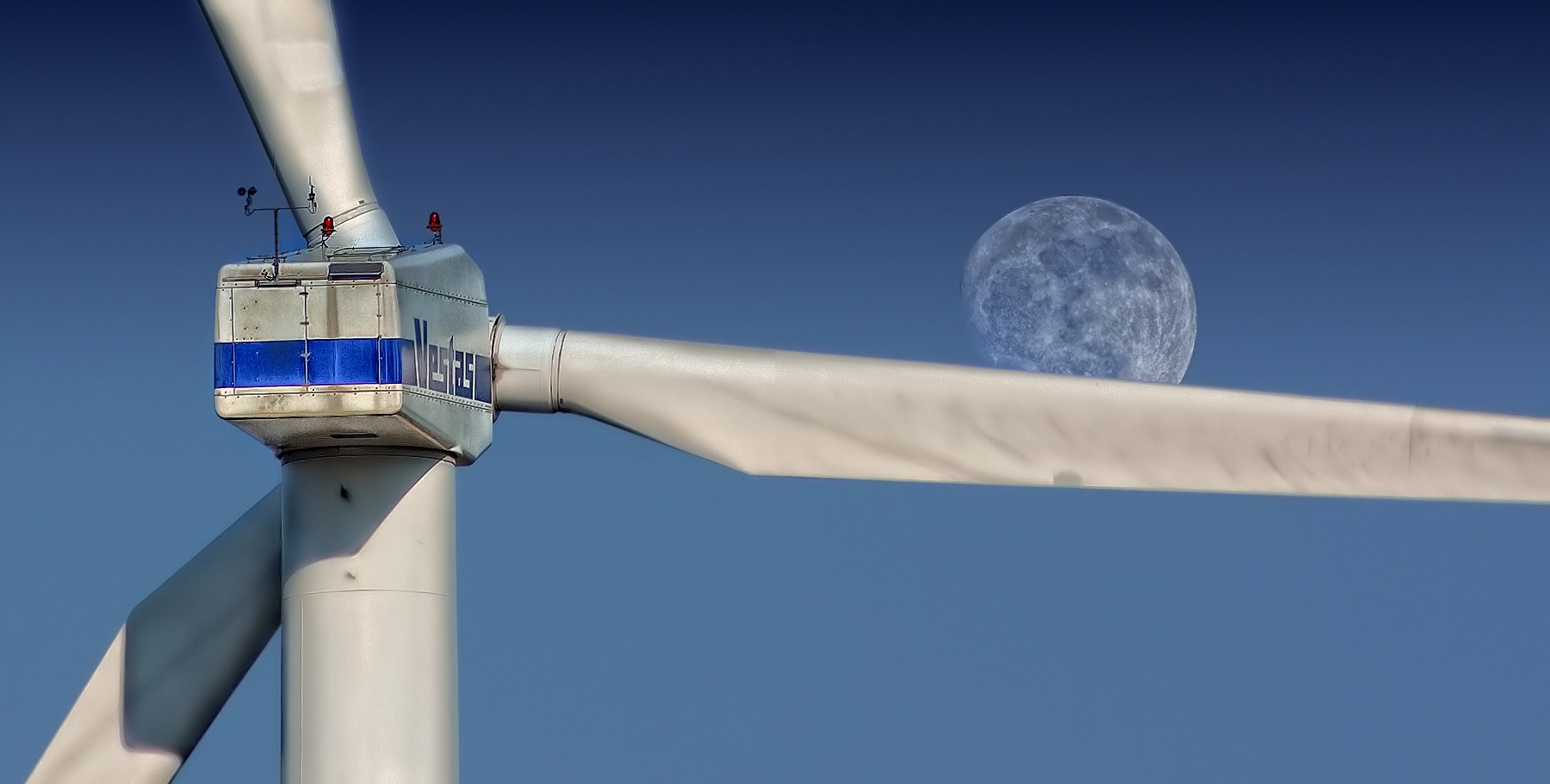 A wind turbine with the moon in the background