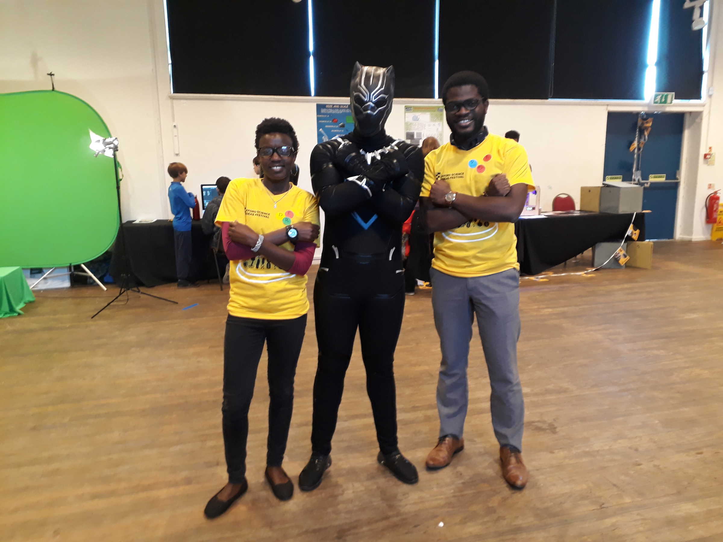 Two students stand either someone of person dressed as Marvel superhero Black Panther