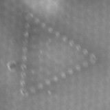 A grey background with a triangle made up of circles pointing to the right