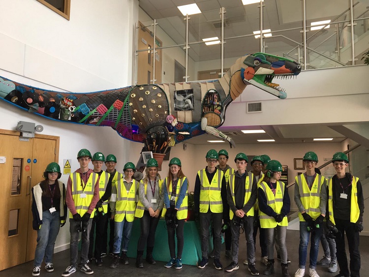 Group of school students in safety wear infront of a robot t-rex