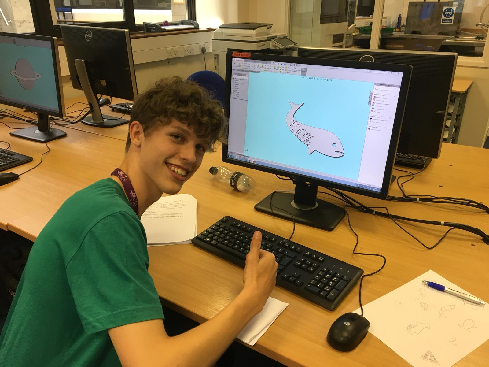 Student sat at computer giving thumbs up to camera