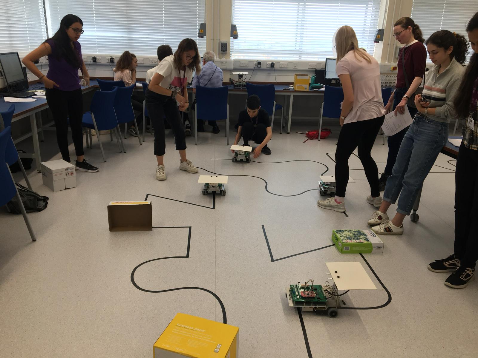 Group of students looking at many small robots