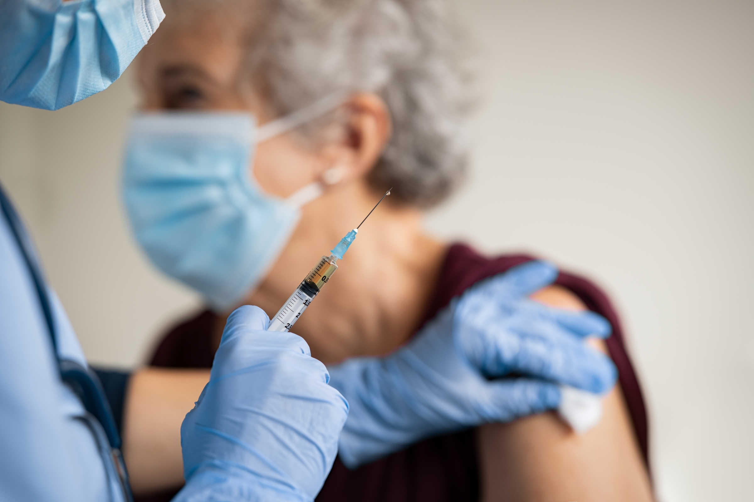 Doctor wearing PPE gives elderly woman a vaccine