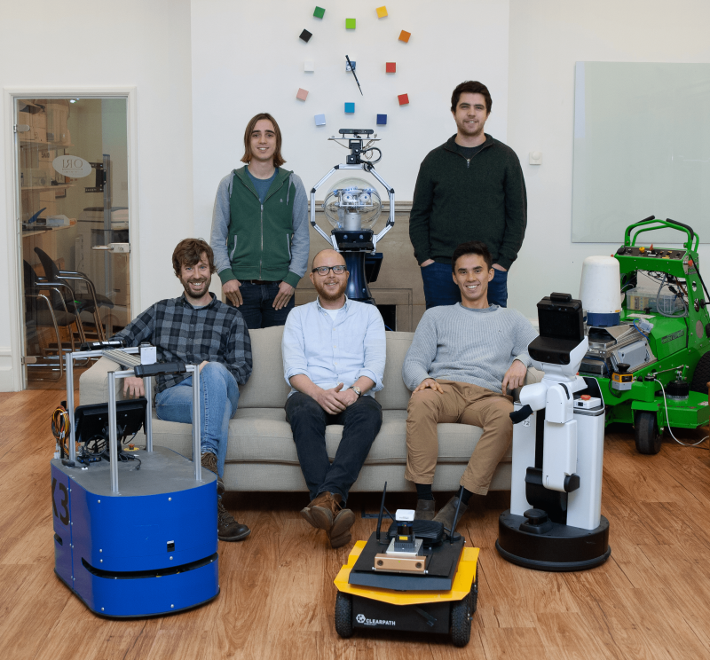 GOALS group photo sitting on lounge with robots in front. 