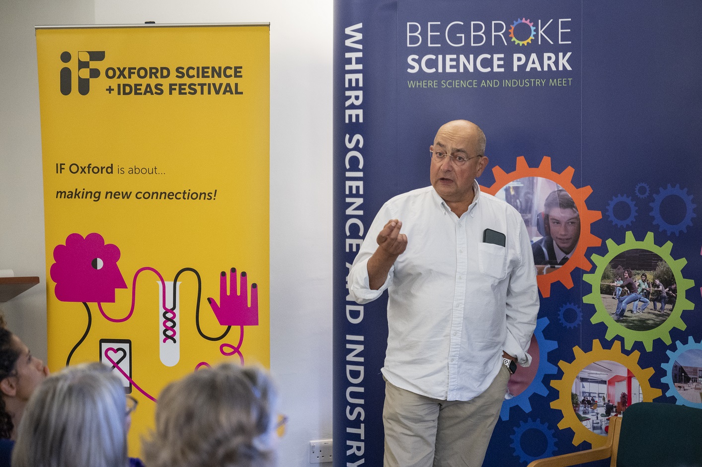 A low resolution image of Professor Ian Thompson stood in front of two roller banners, talking to an audience.