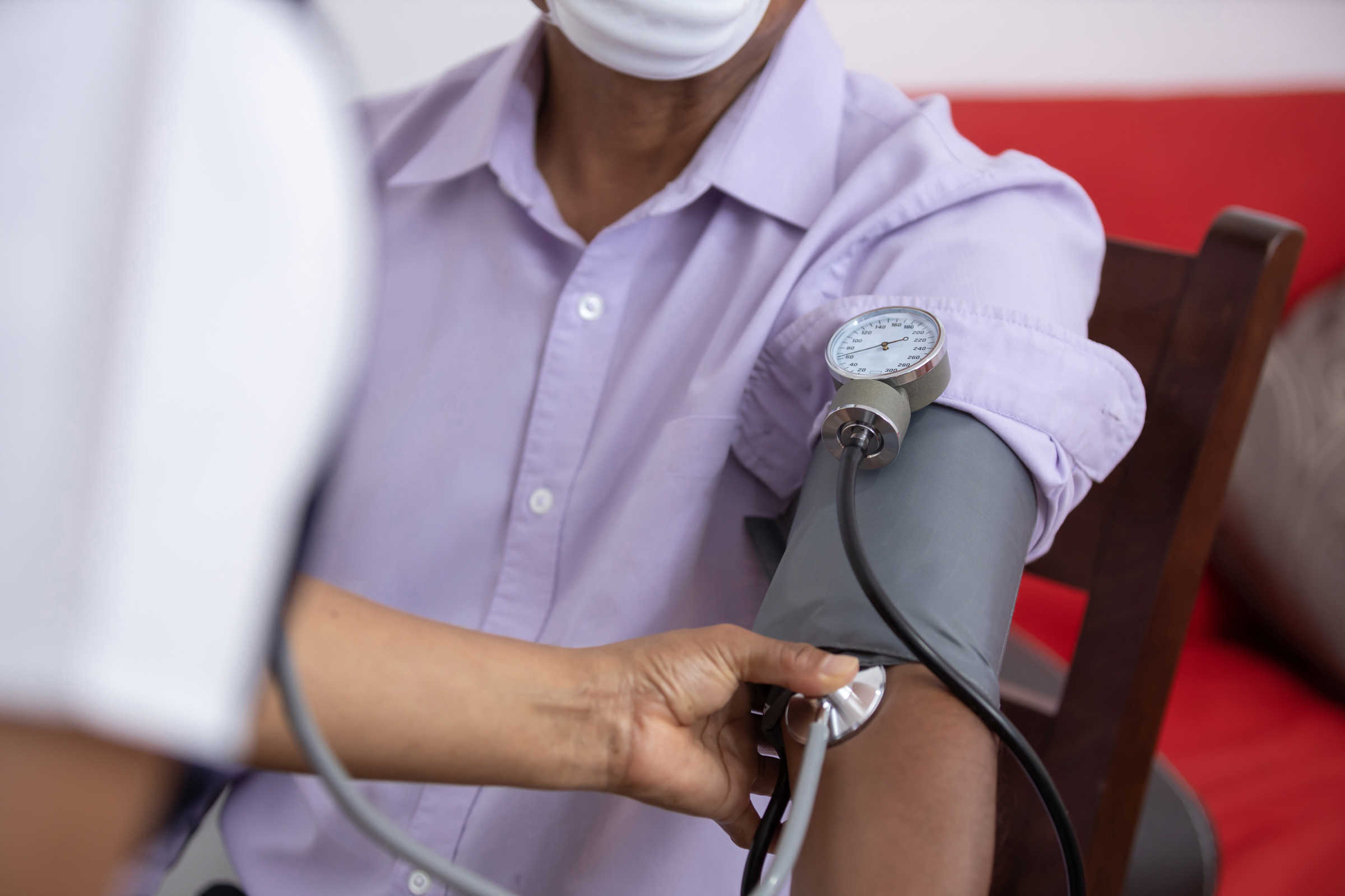 Nurse takes blood pressure of patient wearing mask