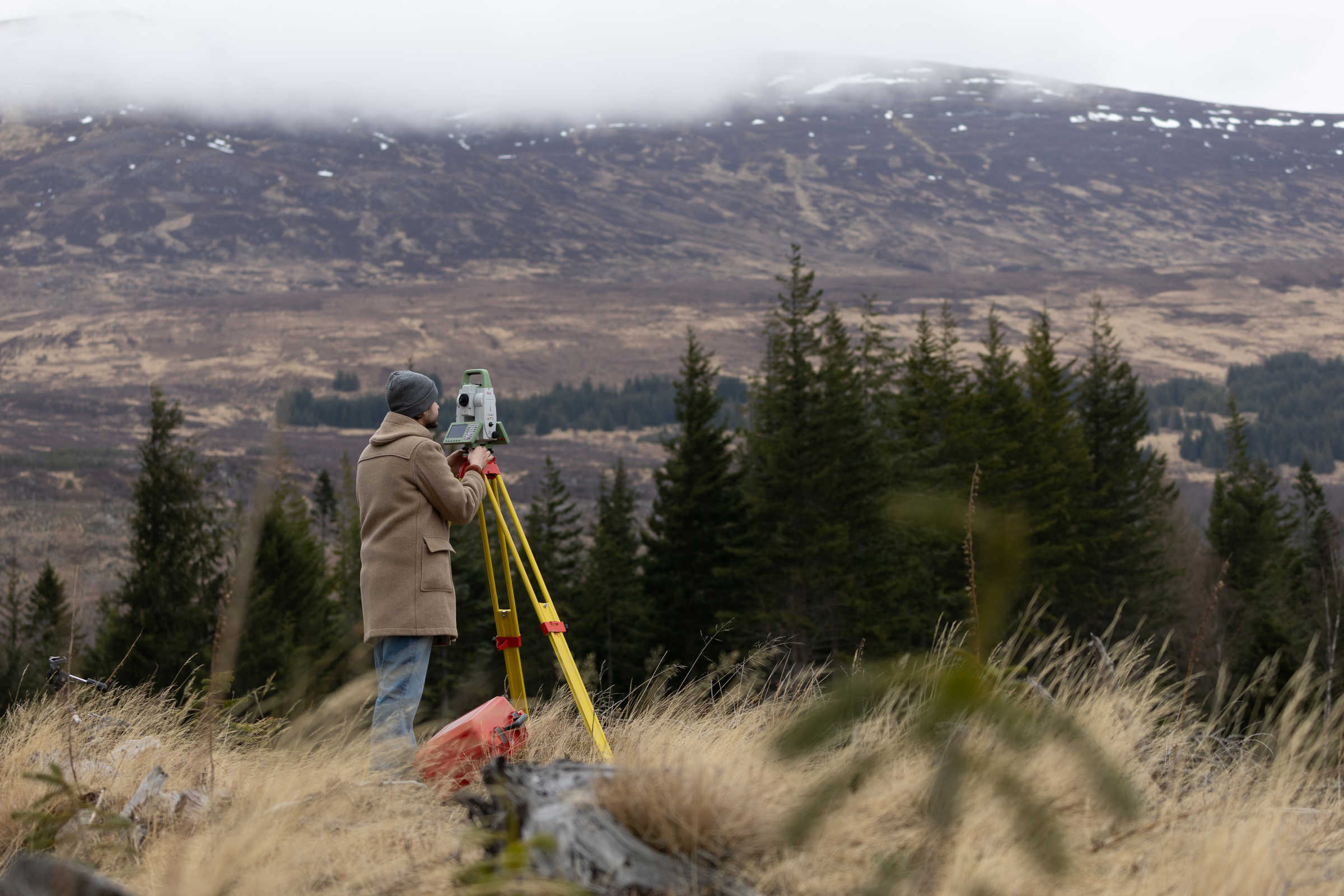 Man looking through Leica Laser Tracker with Scottish mountains in background. 
