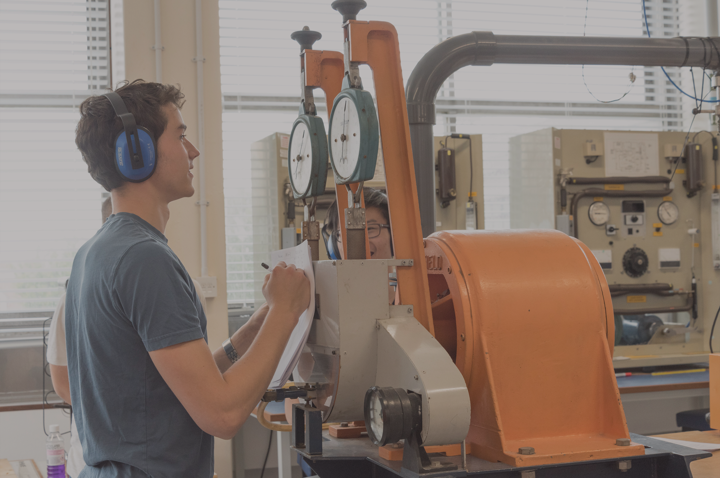 Student wear ear protectors and taking readings from dials on large instrument